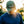Man wearing a green cap with 'RK' logo, standing outdoors with sunlight filtering through.