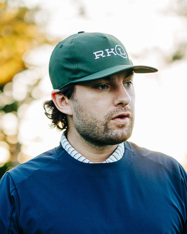 Man wearing a green cap with 'RKL' logo outdoors